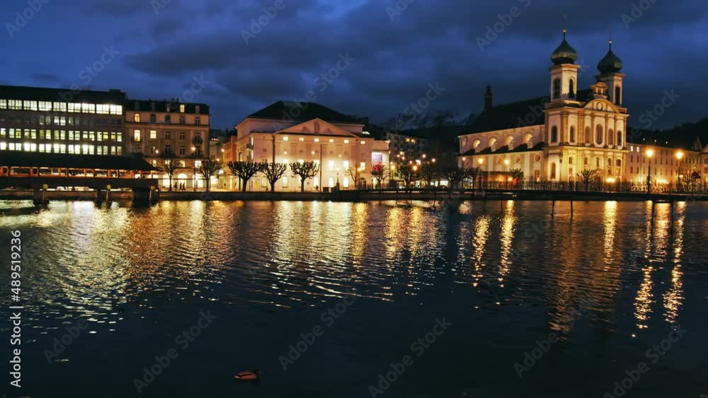 A beautiful reflection of the historical medieval buildings of Lucerne at night. People walk at night on the bridge in Lucerne City by Chapel Bridge Kapellbrücke, Switzerland. A beautiful reflection of the historical medieval buildings of Lucerne at night. People walk at night on the bridge in Lucerne City by Chapel Bridge Kapellbrücke, Switzerland.