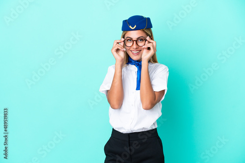 Airplane stewardess Uruguayan woman isolated on blue background with glasses and surprised