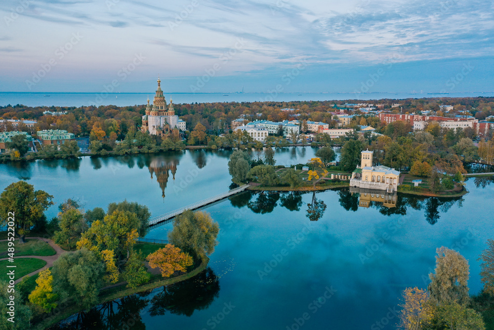 Obraz premium Panoramic aerial view of Holgin pond and the islands with pavilions in Peterhof,Peter and Paul Cathedral, wooden bridge to the island, reflected in the water, photo for a postcard