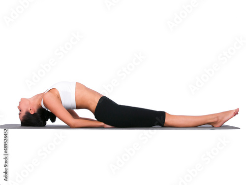 Fototapeta Naklejka Na Ścianę i Meble -  Stretching her lower back. A young woman doing stretches while isolated on white.