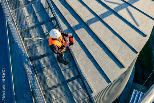 Top view of an industry worker standing on height and checking on silo supply. photo
