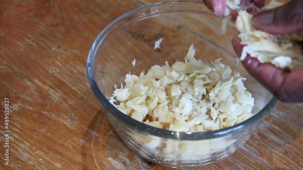 Man of African ethnicity flaking soaked saltfish in preparation for ackee and saltfish, the national dish of Jamaica Man of African ethnicity flaking soaked saltfish in preparation for ackee and saltfish, the national dish of Jamaica