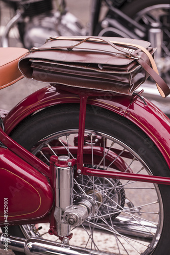The rear part of a vintage motorcycle with a leather boot.
