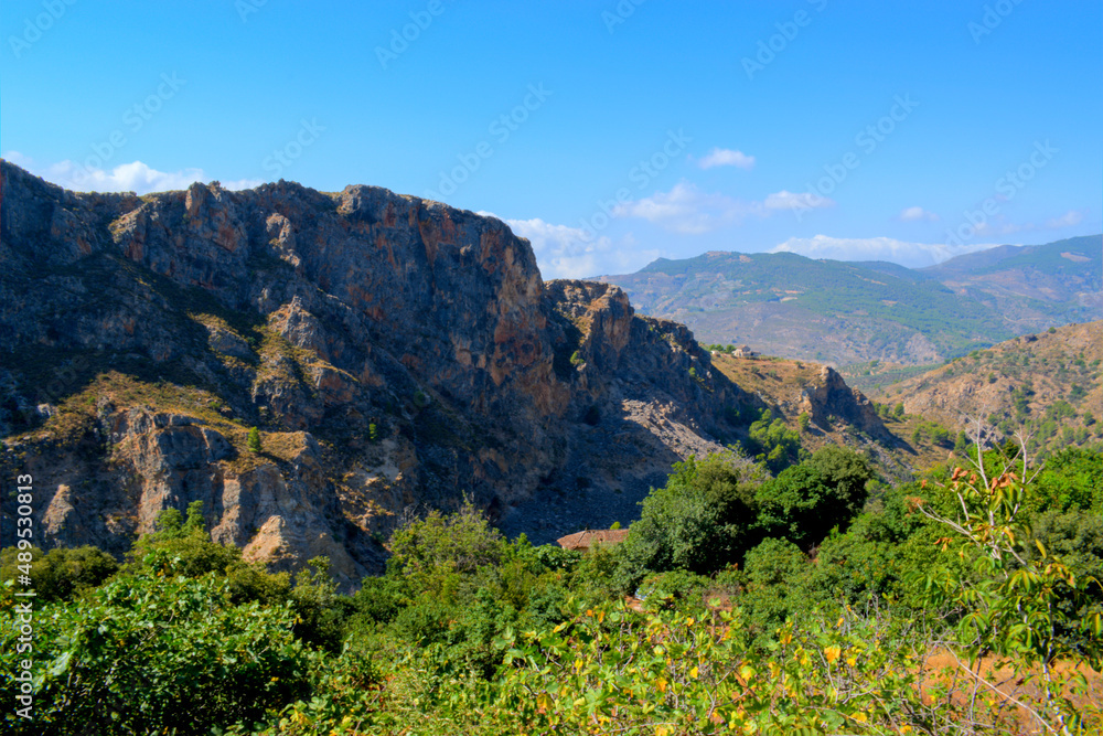 Naklejka premium Grassy mountain with crolling clouds and blue sky.