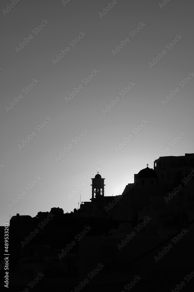 Obraz premium Amazing golden sunset and silhouette view of churches and the village of Imerovigli in Santoriniin black and white 