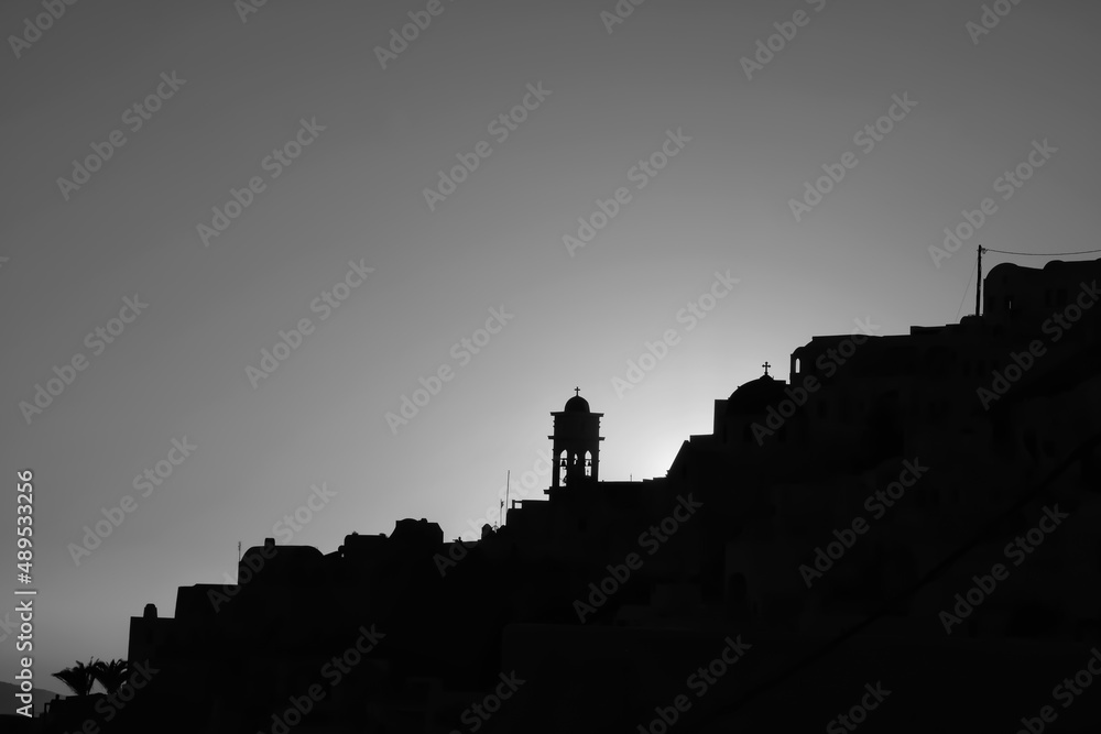 Amazing golden sunset and silhouette view of  churches and the village of Imerovigli in Santorini in black and white 