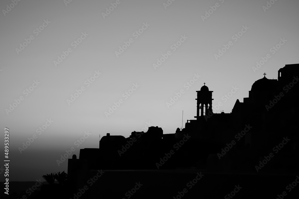 Amazing golden sunset and silhouette view of  churches and the village of Imerovigli in Santorini in black and white 