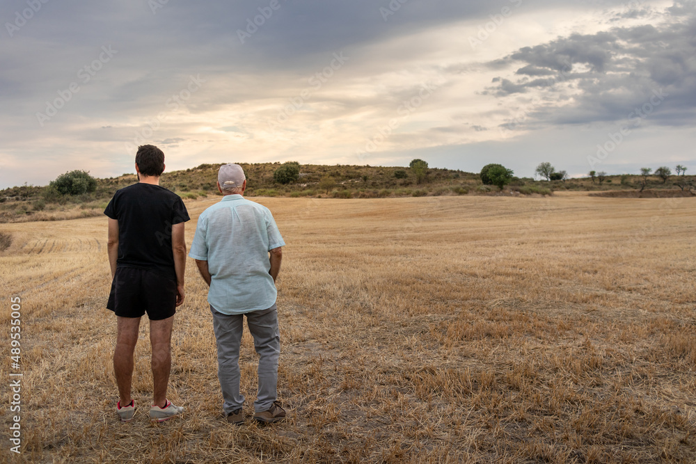 Father and son at the countryside working in agriculture, harvested fields at summer time, rural landscape at sunset time in Huesca, Aragon, Spain