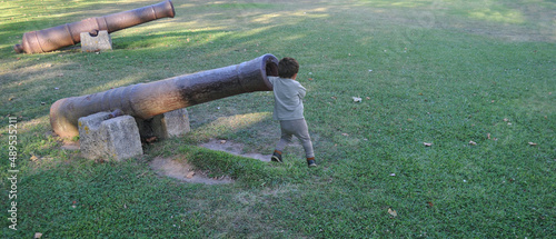 Criança a brincar com um canhão antigo, braço dentro do cano do canhão  photo