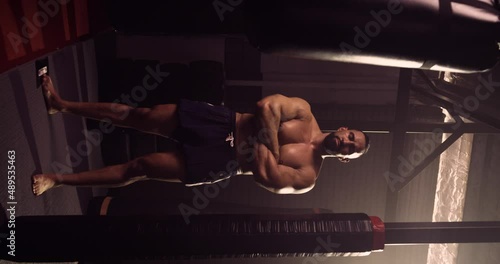 A Vertical Video Portrait Of A Hispanic Bodybuilder In An MMA Gym. Shot In A Crossfit Boxing Gym With Low Key Lighting And A Scattering Of Haze. Captured On Red Digital Cinema Camera 