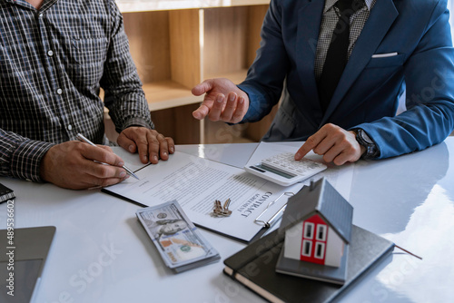 Discussion With A Real Estate Agent, a businesswoman signing a contract for Insurance protecting house, a real estate home is pointing to insurance contract signing and are explaining to customers.