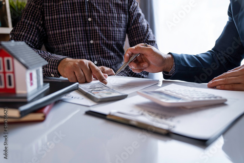 Discussion With A Real Estate Agent, a businesswoman signing a contract for Insurance protecting house, a real estate home is pointing to insurance contract signing and are explaining to customers.