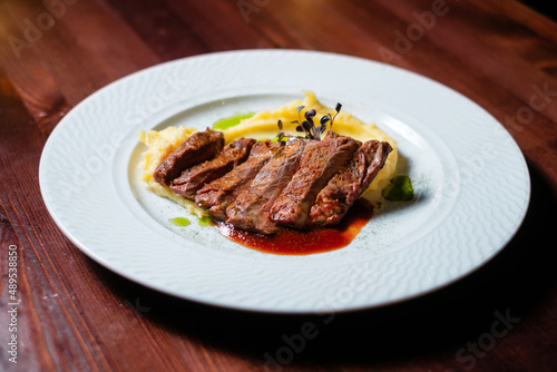 Grilled meat with sauce and mashed potatoes side view.