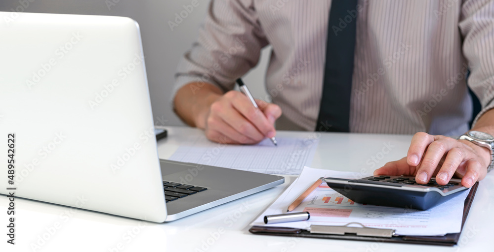 Businessman or accountant using calculator and laptop computer in office, businessman working at home, finance, marketing and accounting concept. Businessman or accountant using calculator and laptop computer in office, businessman working at home, finance, marketing and accounting concept.