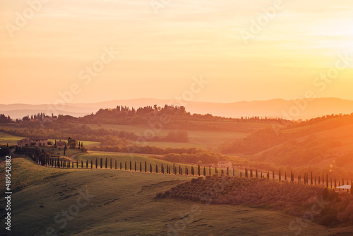 landscape of hills, country houses and trees in tuscany at sunset