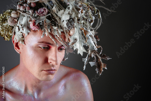 Photos The face of a male model in a headdress of flowers filled with wax