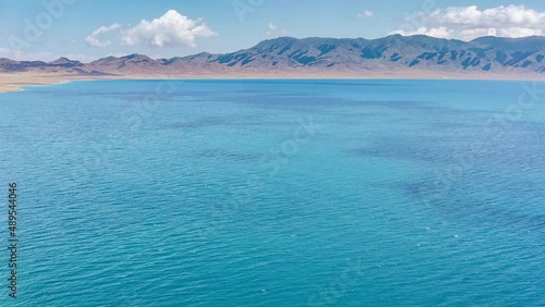 Aerial footage of blue Sayram Lake and mountain natural landscape in Xinjiang, China. Sailimu Lake is the alpine lake with the highest altitude, largest area and beautiful scenery in Xinjiang.