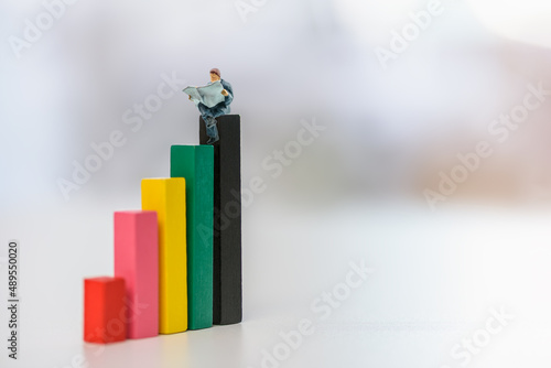Konstfotografi Retirement, pension income tax and social security benefit concept : Young retiree sits on the highest top rank wood pole and reads a newspaper, depicting early retirement to escape from the rat race