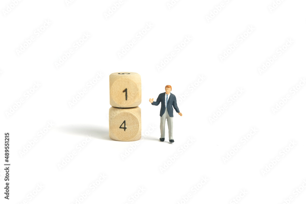 Miniature people toy figure photography. A shrugging businessman standing beside wooden dice. Isolated on white background. Image photo Miniature people toy figure photography. A shrugging businessman standing beside wooden dice. Isolated on white background. Image photo