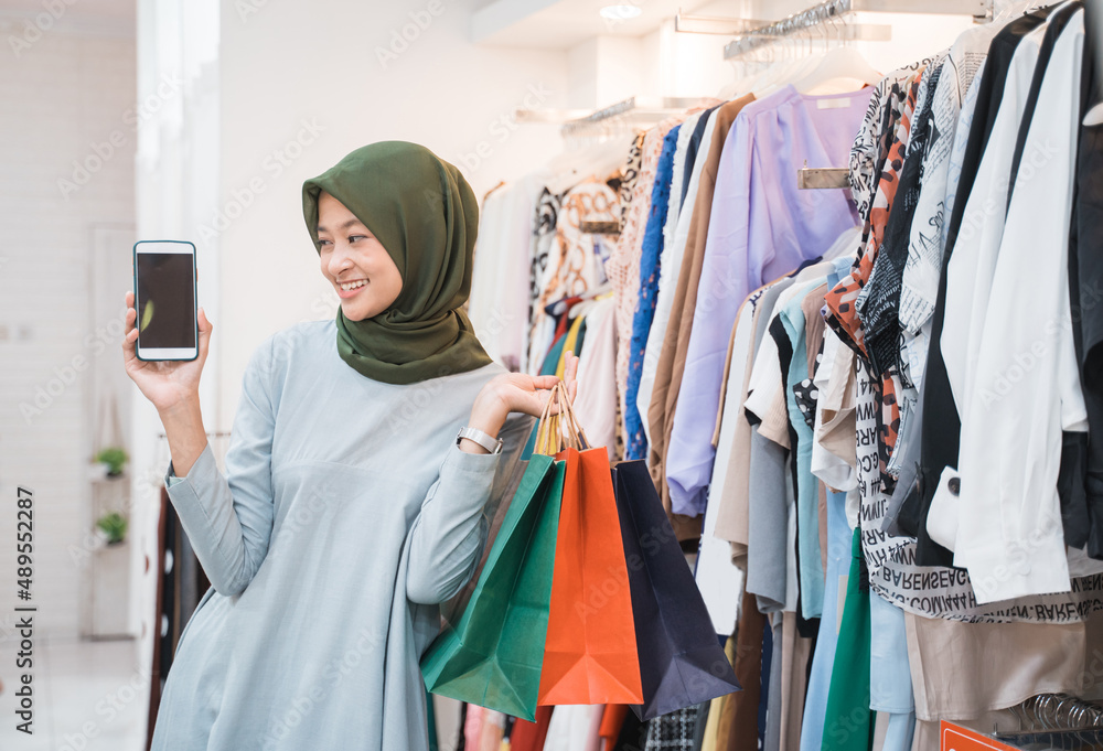 beautiful girl wearing a hijab holding a smartphone and showing to camera beautiful girl wearing a hijab holding a smartphone and showing to camera