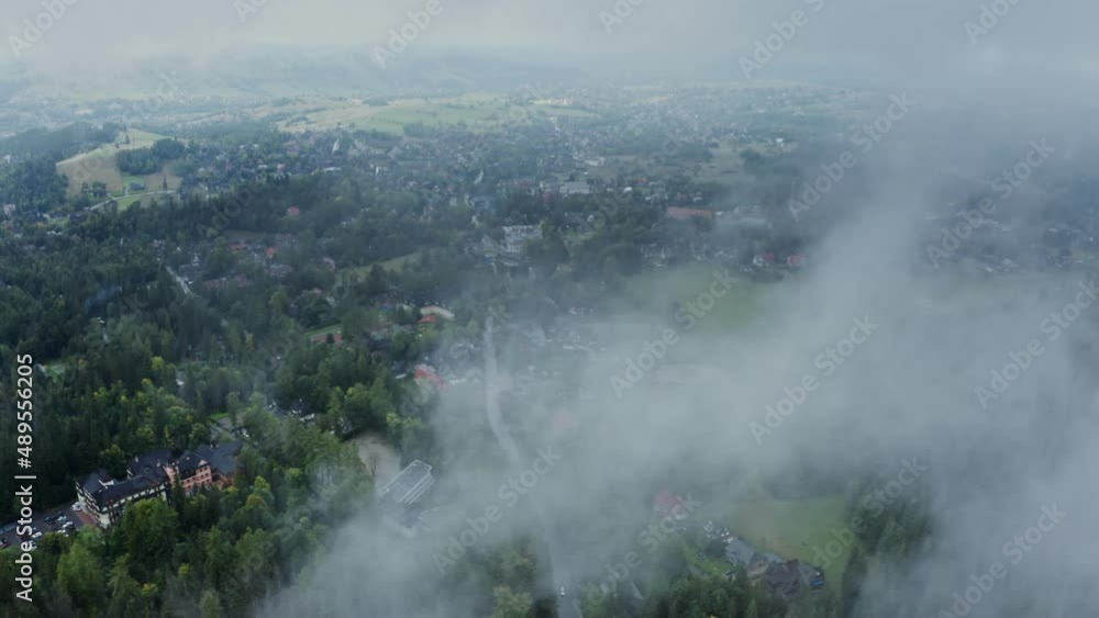 Video from a drone, a view of a city located in a spruce forest near a field