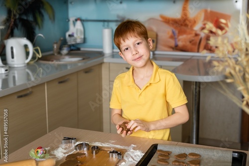 Cooking cookies at home for Easter red-haired boy in a yellow t-shirt cooks in the kitchen