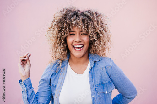 portrait of smiling hispanic woman with afro hair in city during spring. Urban lifestyle