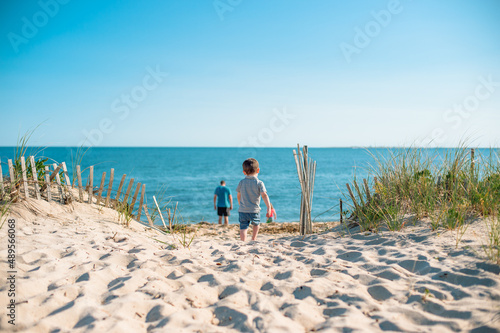 Foto A toddler on a beach on Cape Cod stops playing with a bucket and walks down the