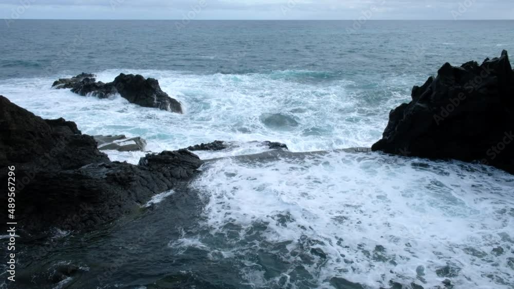 Ocean waves crashing against the rocks on Madeira Island, Portugal during a cloudy day. Natural rock pool next to the ocean. Cinematic shot. Travel the world.
Ocean waves crashing against the rocks on Madeira Island, Portugal during a cloudy day. Natural rock pool next to the ocean. Cinematic shot. Travel the world.