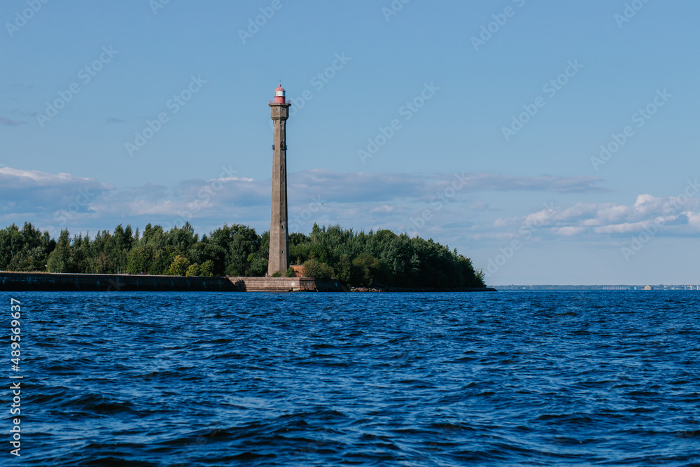 View from the water of the Kronstadt lighthouse, the coastline of Kronstadt, the waters of the Gulf of Finland, the blue sea and waves