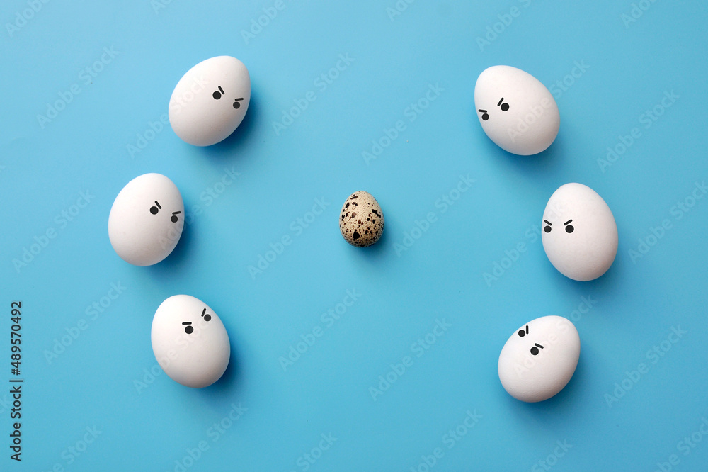 A quail egg surrounded by chicken eggs. Rejection of non-ordinary people in society A quail egg surrounded by chicken eggs. Rejection of non-ordinary people in society
