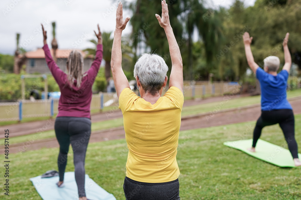 Multiracial senior women doing yoga exercise at city park Multiracial senior women doing yoga exercise at city park