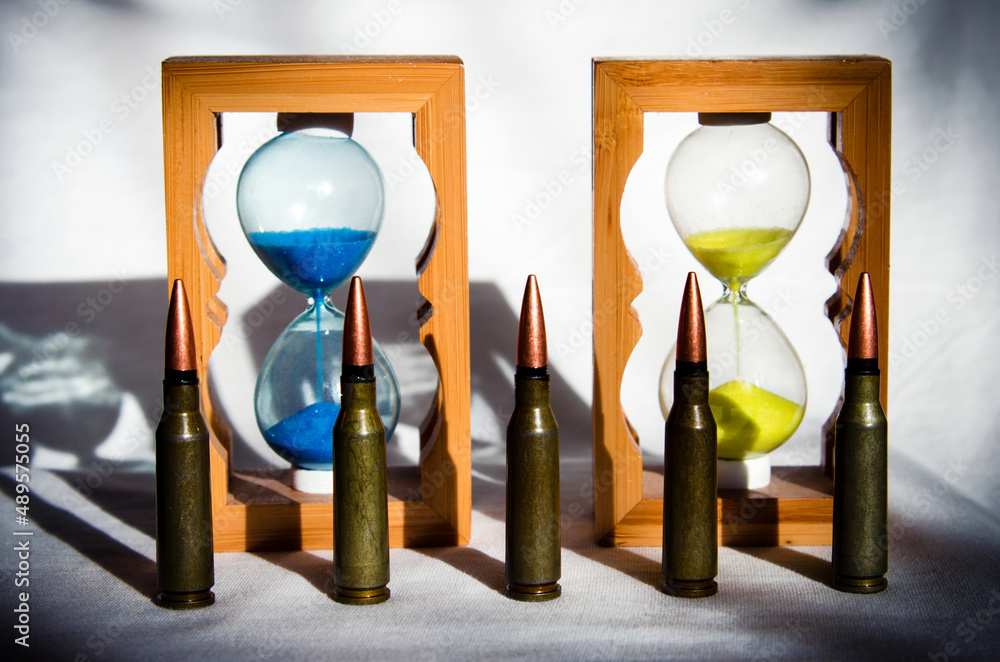 Abstract image of military bullets on the background of an hourglass with the colors of the flag of Ukraine. (War in Ukraine - concept)