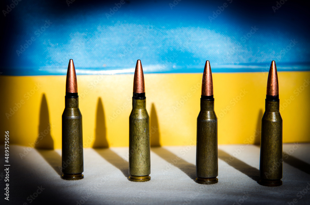 Abstract image of military bullets on the background of the Ukrainian flag (War in Ukraine - concept)