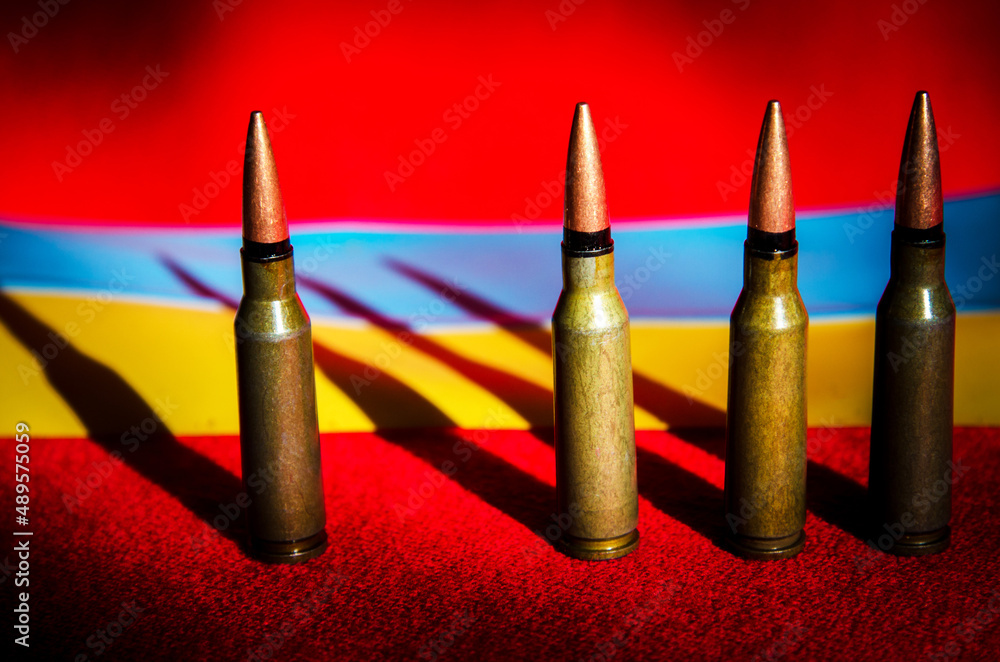 Abstract image of military bullets on the background of the Ukrainian flag and blood color (War in Ukraine - concept)