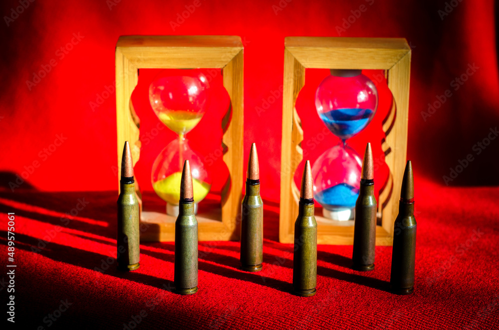 Abstract image of military bullets on the background of an hourglass with the colors of the flag of Ukraine. (War in Ukraine - concept)