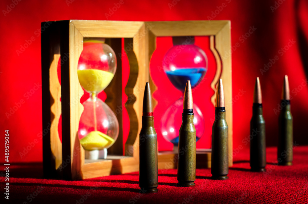 Abstract image of military bullets on the background of an hourglass with the colors of the flag of Ukraine. (War in Ukraine - concept)