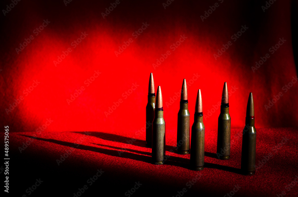 Abstract image of military bullets on a background of blood color. A place for an inscription. (War in Ukraine - concept)