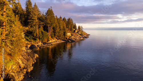 Sunset on the Sunshine Coast: View along the Halfmoon Bay coastline with the sun setting reflected against the trees and water