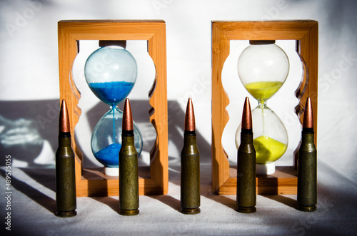 Obraz na płótnie Abstract image of military bullets on the background of an hourglass with the colors of the flag of Ukraine. (War in Ukraine - concept) w salonie