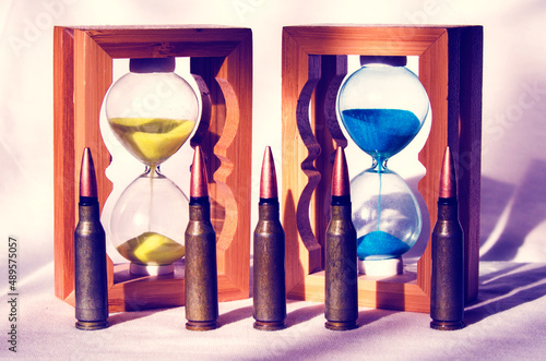 Abstract image of military bullets on the background of an hourglass with the colors of the flag of Ukraine. (War in Ukraine - concept)