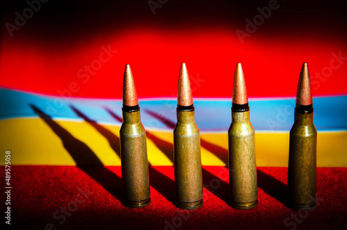Abstract image of military bullets on the background of the Ukrainian flag and blood color (War in Ukraine - concept)