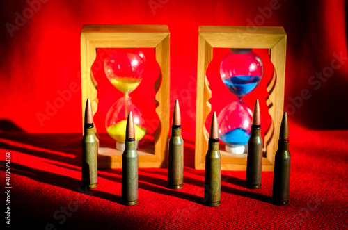 Obraz na płótnie Abstract image of military bullets on the background of an hourglass with the colors of the flag of Ukraine. (War in Ukraine - concept) w salonie