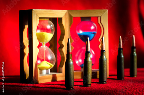 Abstract image of military bullets on the background of an hourglass with the colors of the flag of Ukraine. (War in Ukraine - concept)