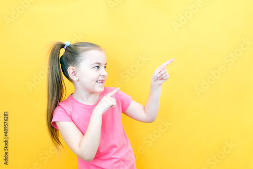 Wow, look, advertise here! Portrait of an amazed cute girl pointing at an empty space in the background