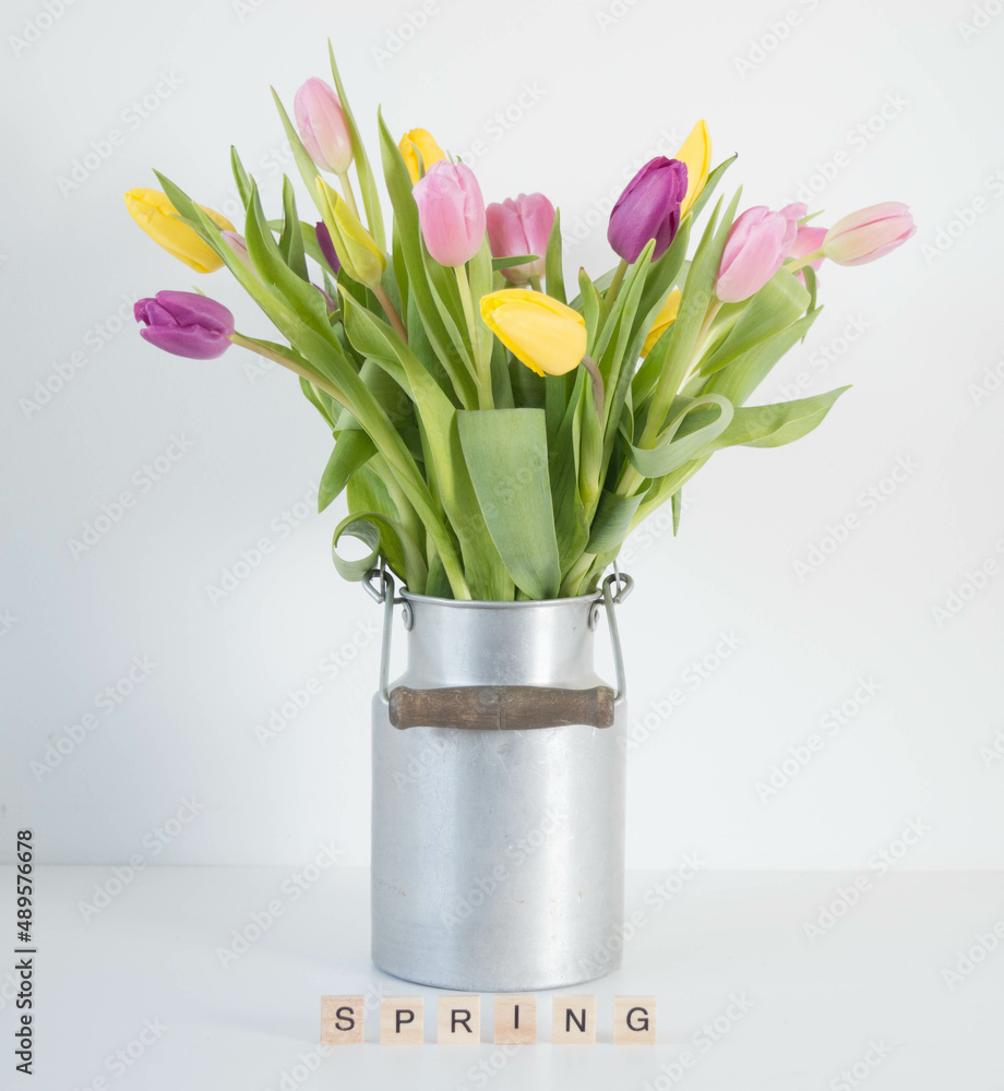 pink, yellow and purple tulips in silver metal milk can with wooden letters