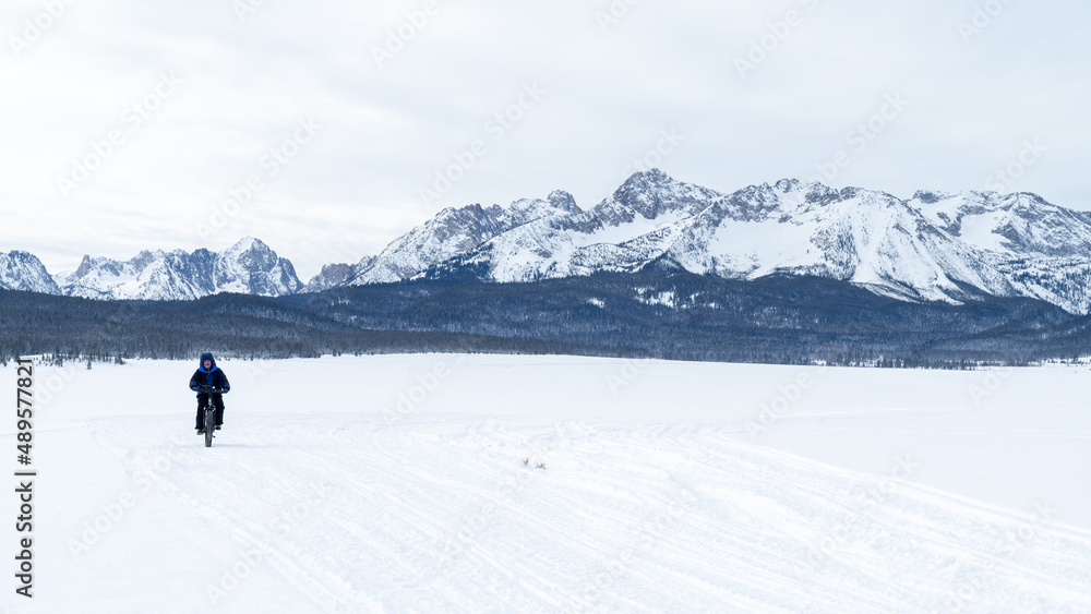 Man rides a fat tire bike on the snow with Idaho Sawtooth Mountain backdrop