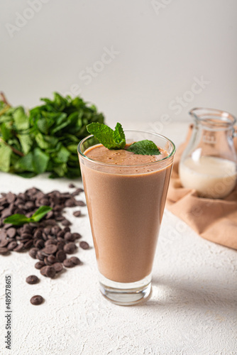 chocolate protein milkshake in glass white kitchen background. delicious portion chocolate milkshake. healthy protein shake on vegan milk