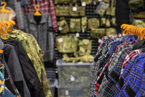 Department in the men's military clothing store. Camouflage uniforms hang on hangers in a military store