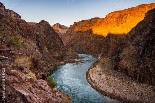 Bright Orange Light Warms The Rocks Above The Colorado River At Sunrise